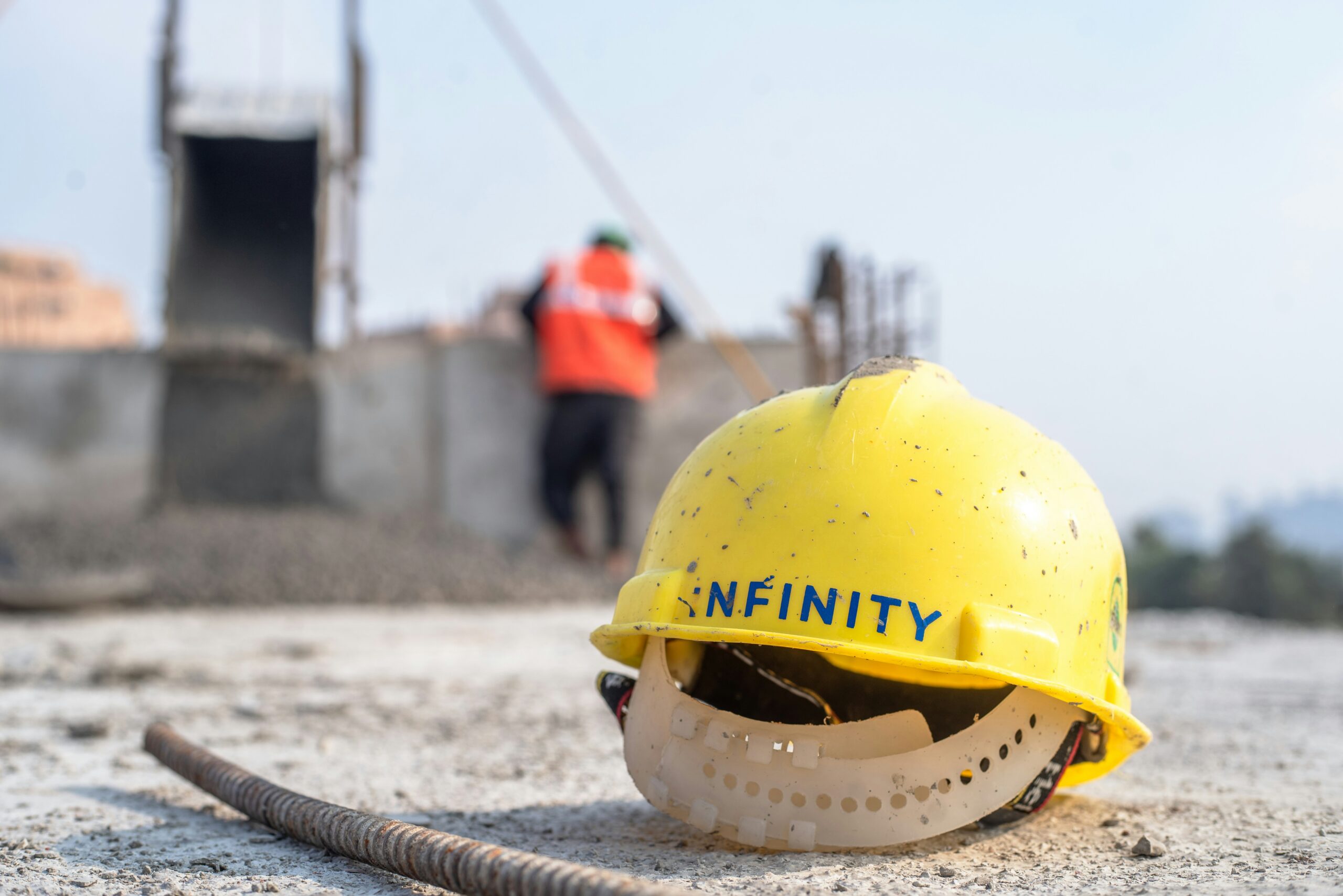 A yellow hard hat sitting on top of a cement ground